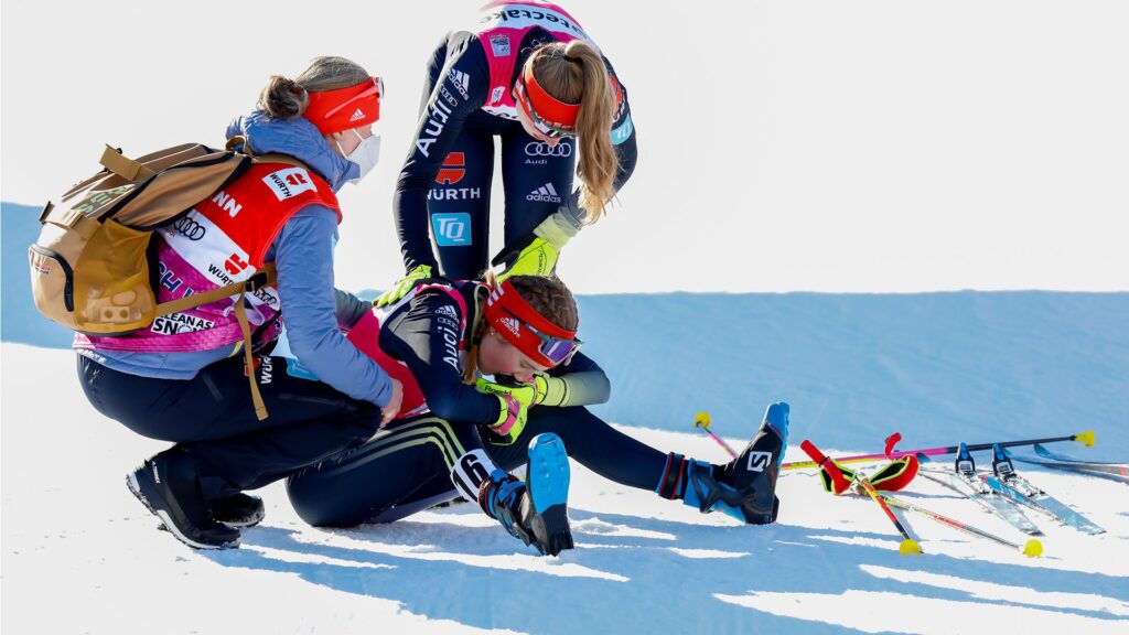 Eine DSV-Läuferin sitzt nach dem Langlauf-Rennen in der Nordischen Kombination im Ziel erschöpft am Boden